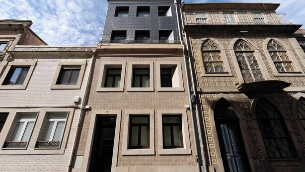 Um edifício de vários andares com uma mistura de estilos arquitetônicos, incluindo uma fachada moderna e janelas em arco tradicionais.