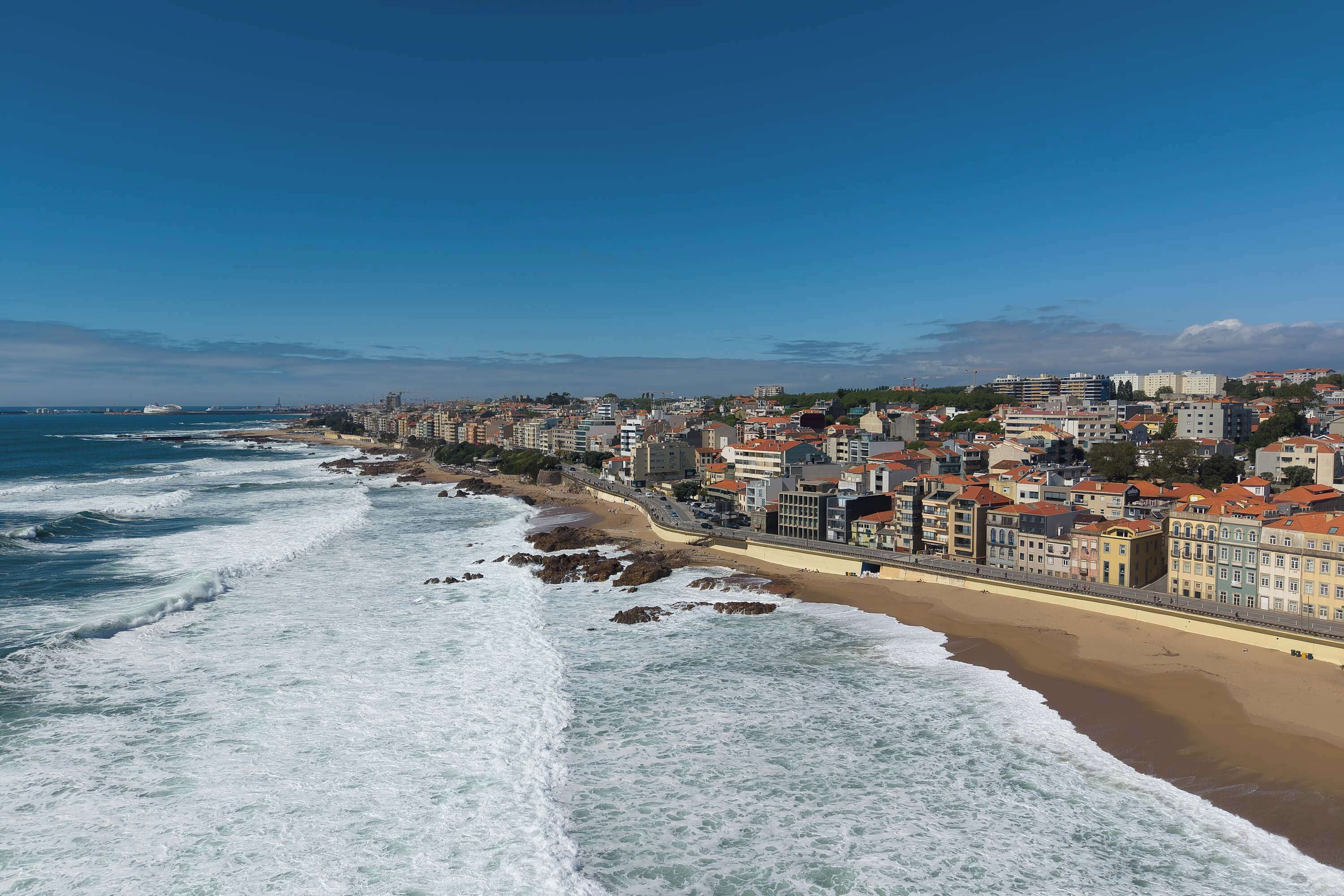 Un paisaje costero urbano con un paseo marítimo y edificios a lo largo de la orilla.