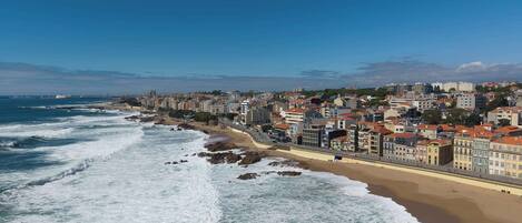 A coastal cityscape with a beachfront promenade and buildings along the shore.
