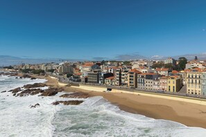 Un paysage urbain situé sur la côte, avec une plage de sable, une promenade et différents types de bâtiments.