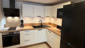 Una cocina moderna con gabinetes blancos, un refrigerador negro, horno integrado y microondas.