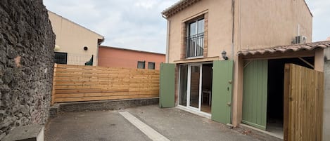 Un immobile residenziale con vialetto lastricato, recinzione in legno, un balcone e una porta verde.