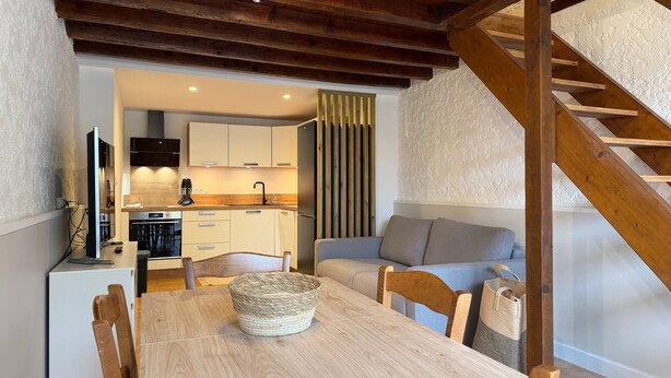 Una cocina moderna con armarios de madera, una mesa de comedor y una escalera.
