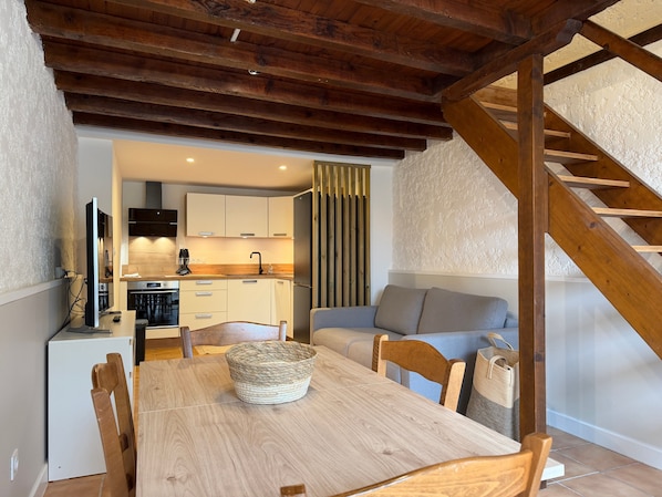 A modern kitchen with wooden cabinets, a dining table, and a staircase.