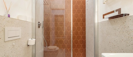 A modern bathroom with a glass-enclosed shower, a white sink, and a toilet.