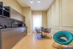 Una cocina moderna con comedor, una silla color turquesa y un ventanal con cortinas.