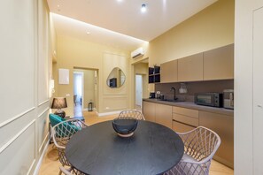 Una cocina moderna con zona de comedor, que presenta una mesa redonda con sillas, horno empotrado y microondas.