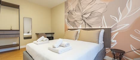 A hotel room with a large bed, a bedside table, a mirror, and a wall with a floral design.