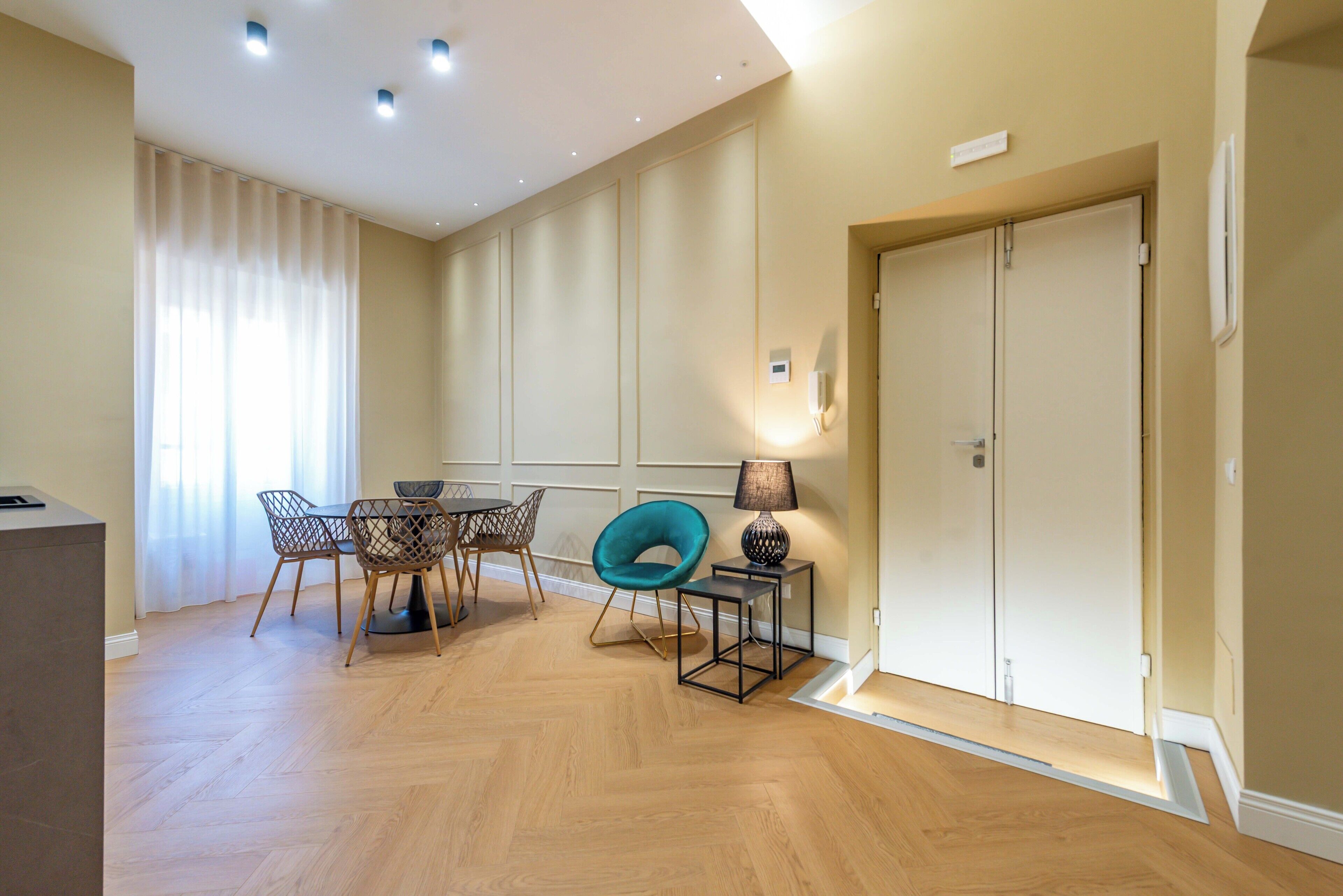 Un coin repas avec une table ronde, des chaises, une lampe et une porte.