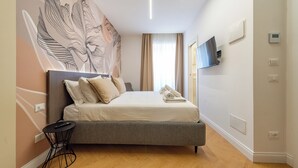 Una habitación de hotel moderna con cama, televisor de pantalla plana y termostato fijado a la pared.