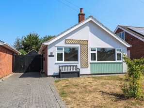 A single-story house with a brick exterior, a white front facade, and a green door. - Pinecote Cottage (Nottingham)