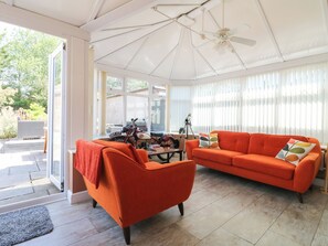 Ein Wintergarten mit Deckenventilator, einem roten Sofa und einem Motorrad.