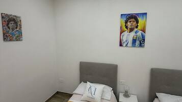 Ein Hotelzimmer mit zwei Betten, einem kleinen Nachttisch mit einem Glas und einem Bild an der Wand.