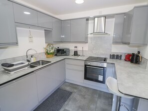 Una cocina moderna con armarios grises, horno empotrado, microondas y cafetera.