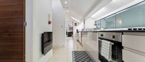 A modern kitchen with a built-in oven, a microwave, and a stainless steel countertop.