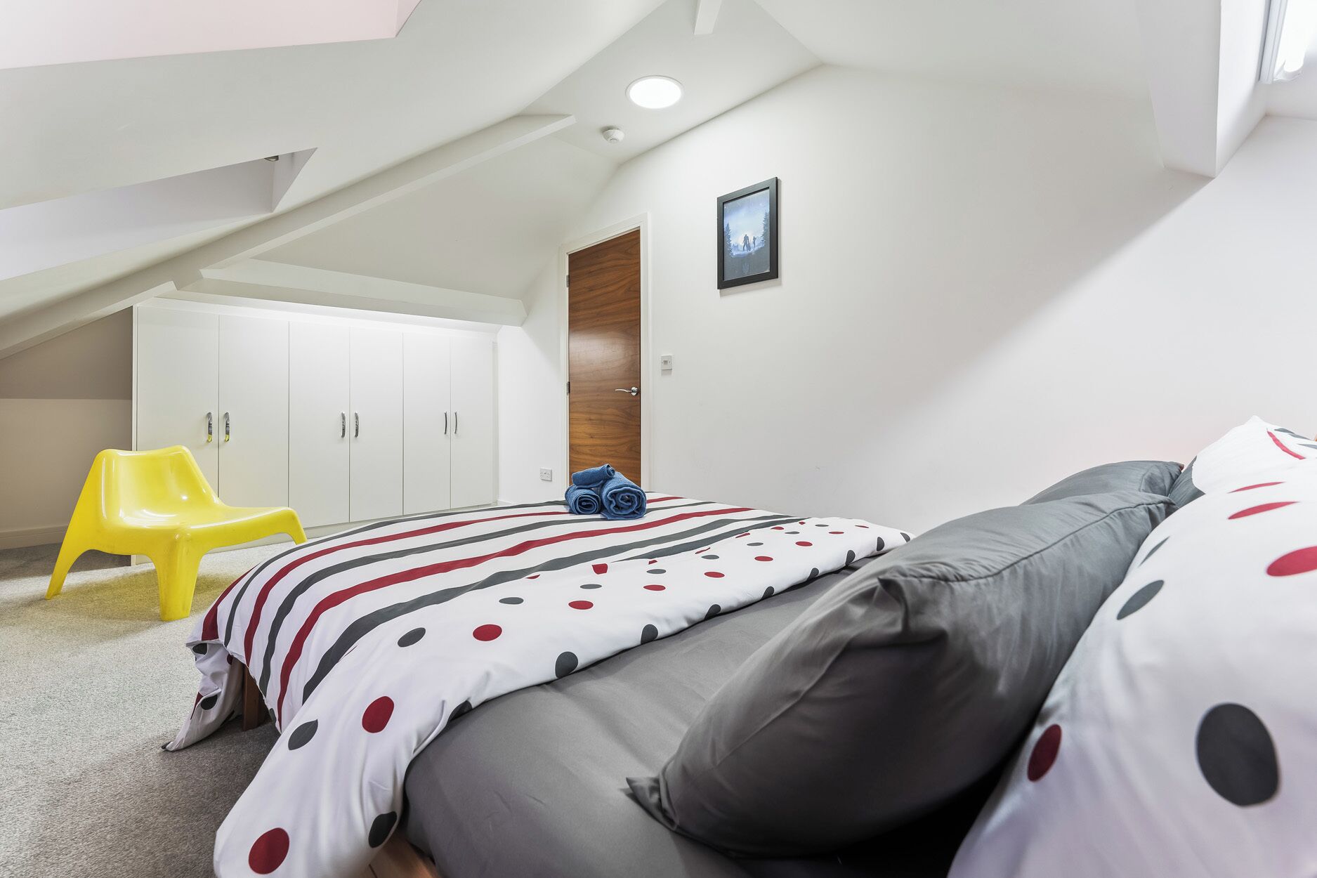 A bedroom with a bed, a chair, and a wardrobe.