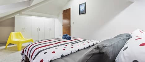 A bedroom with a bed, a chair, and a wardrobe.