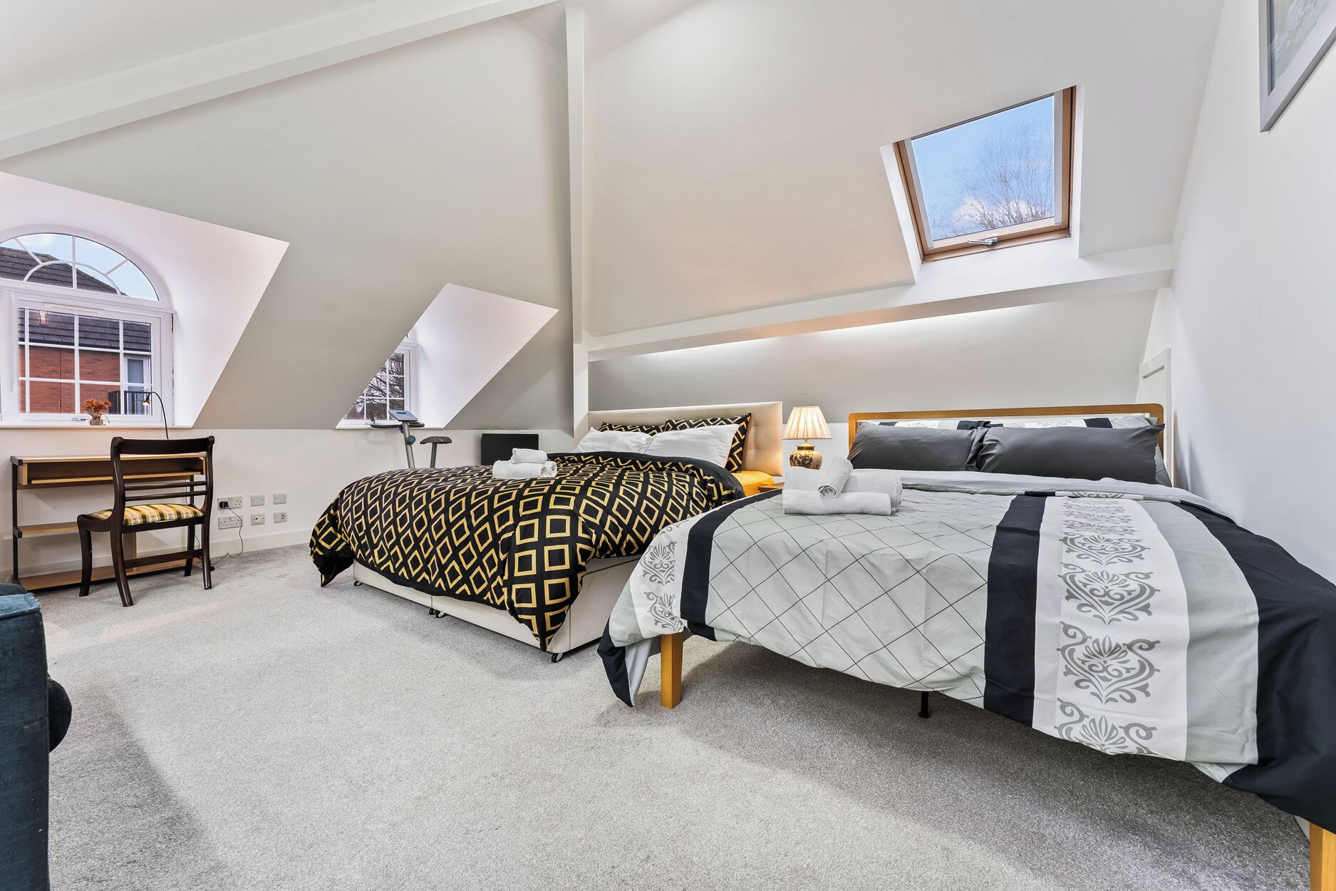Un dormitorio con dos camas, un escritorio y una silla.
