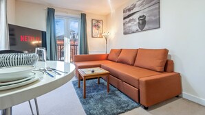 Una sala de estar con sofá, una mesa de centro, televisión y un cuadro en la pared.