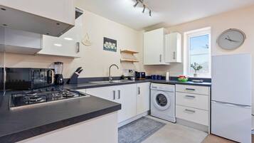 A modern kitchen with a gas stove, coffee maker, and a washing machine.