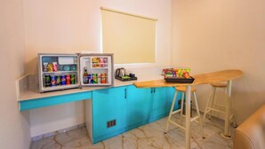 A kitchenette with a fridge, a microwave, a coffee maker, and a small bar area with stools. - King Resort (Marakkanam)