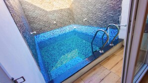 A glass-enclosed hot tub with a tiled interior and a metal ladder. - King Resort (Marakkanam)