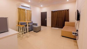 Un salon moderne comprenant un canapé, une petite table, un téléviseur fixé au mur et un appareil de climatisation.
