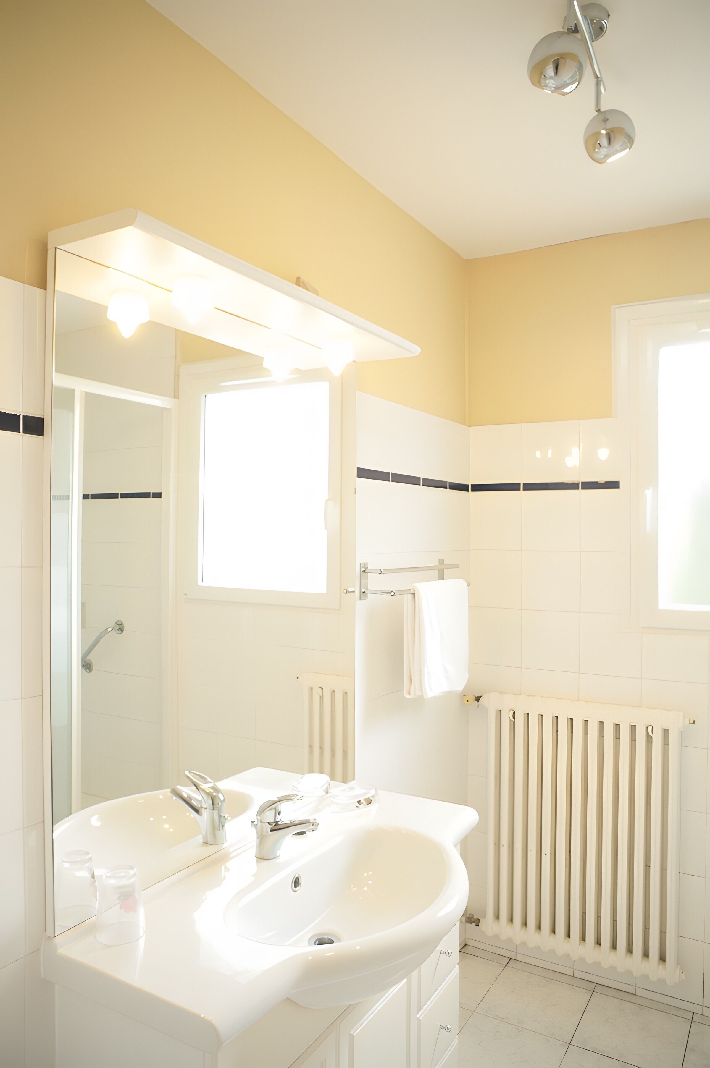 A bathroom with a white sink, a mirror, a towel rack, and a window.
