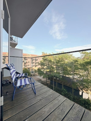 Ein Balkon mit Holzboden und zwei gestreiften Liegestühlen.