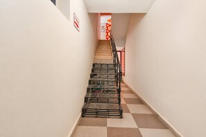 A narrow hallway with a staircase leading to a door with a red and white sign. - Super Collection O Tennati Park Vizag (Visakhapatnam)