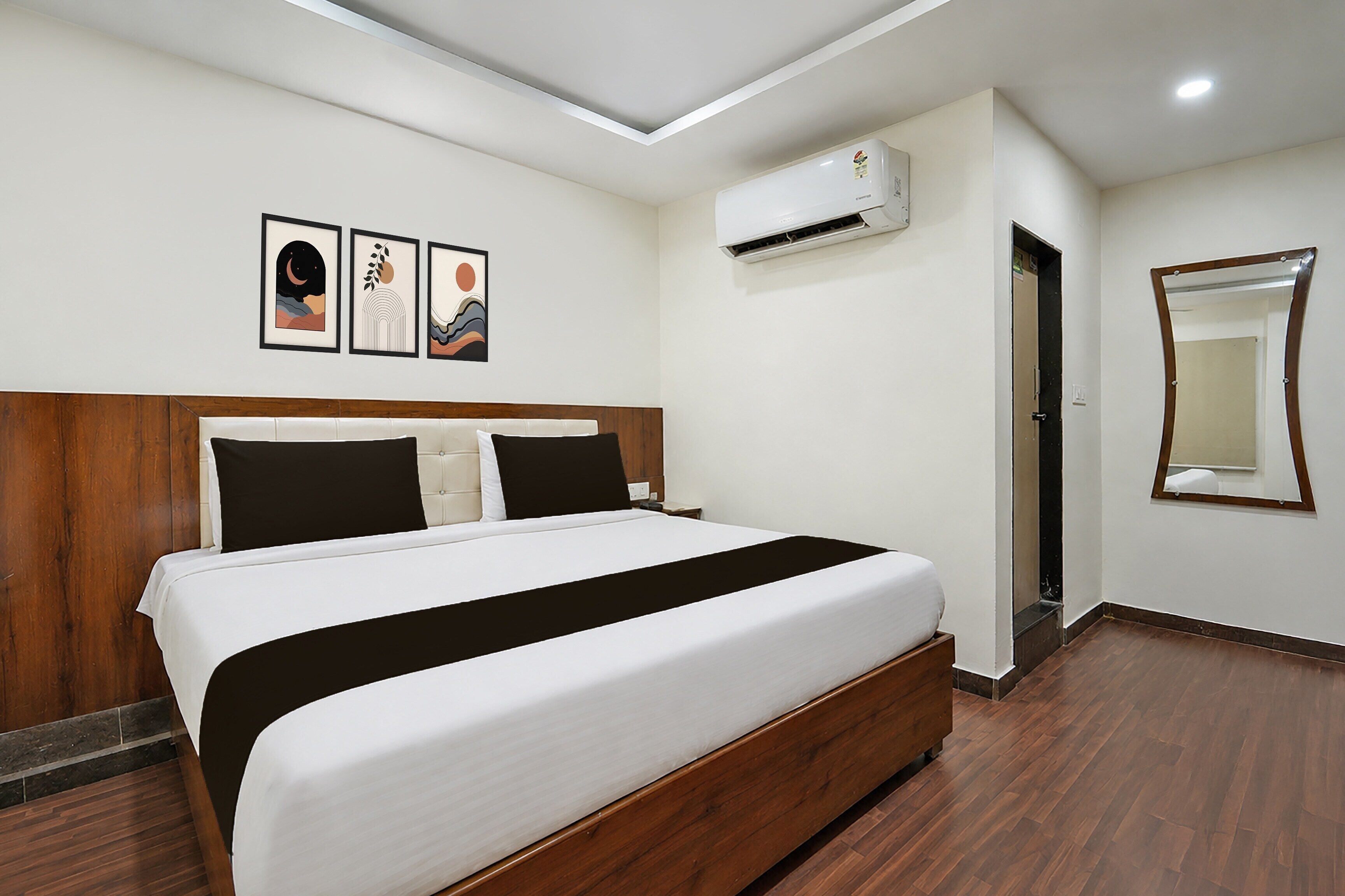 Una camera d'albergo con un letto, un condizionatore d'aria a parete e un quadro incorniciato sopra il letto.