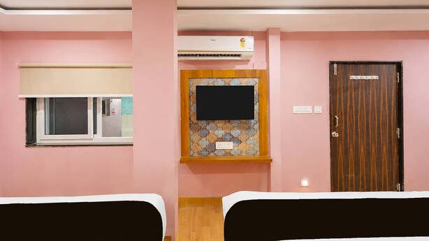 Une chambre d’hôtel avec deux lits, une fenêtre avec un store, un téléviseur fixé au mur et une porte avec une pancarte.