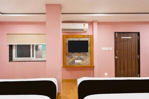 Una habitación de hotel con dos camas, una ventana con persiana, un televisor montado en la pared y una puerta con un letrero.