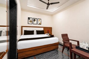 Una habitación de hotel con cama, una silla, un escritorio y un ventilador de techo.