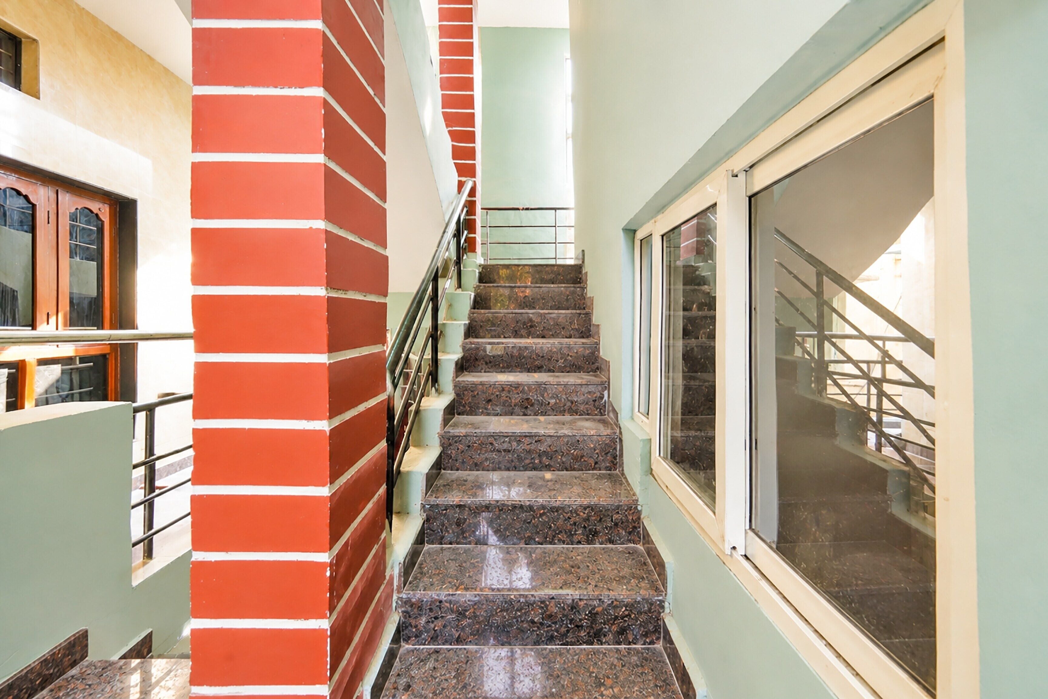 Una escalera con un muro de ladrillo rojo a un lado y una ventana al otro.