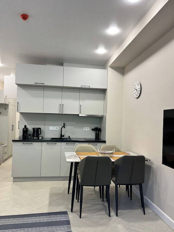 A modern kitchen with white cabinets, a black countertop, and a dining area with a table and chairs.