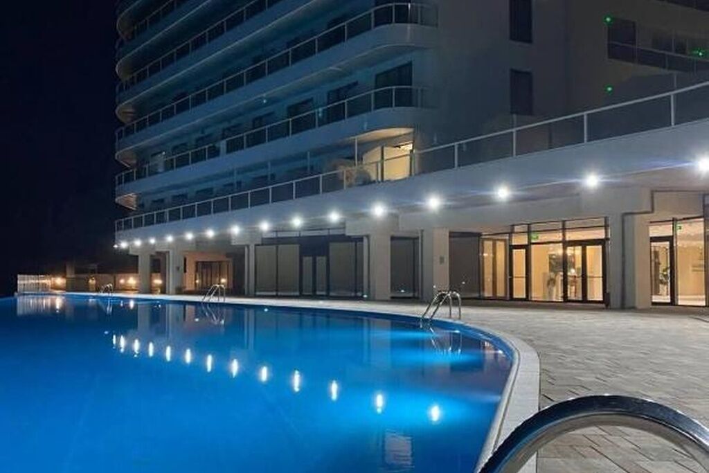 A swimming pool with a clear view of a multi-story hotel building in the background.