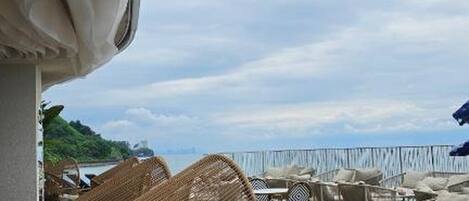 An outdoor seating area with wicker furniture and a view of the sea.
