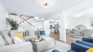 Una sala moderna con una escalera, un comedor y una cocina.
