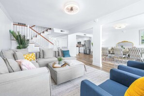 Ein modernes Wohnzimmer mit Treppe, Essbereich und Küche.