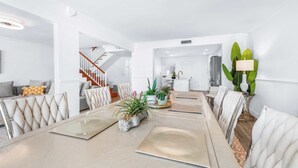 Una sala de estar moderna con comedor, una escalera y una cocina al fondo.