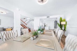 Ein modernes Wohnzimmer mit Essbereich, einer Treppe und einer Küche im Hintergrund.