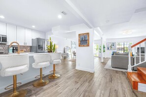Eine moderne Küche mit weißen Schränken, Edelstahlgeräten und einer Bar mit weißen Barhocker.
