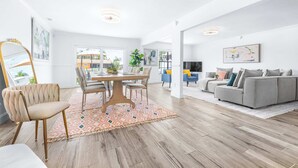 Un salón amplio con mesa de comedor, sofás y un espejo grande.