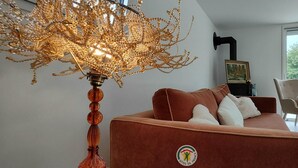 A modern living room with a brown sofa, a decorative lamp, and a view of greenery outside. - La Grange d'Evelyne 4**** (DIZIMIEU)