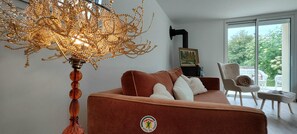 Una sala moderna con un sofá marrón, una lámpara decorativa y vistas a zonas verdes.