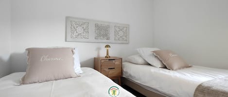 A bedroom with two beds, a nightstand, and decorative wall art.