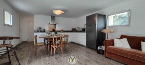 A modern kitchen with white cabinets, a dining table with chairs, a sofa, and a large window. - La Grange d'Evelyne 4**** (DIZIMIEU)