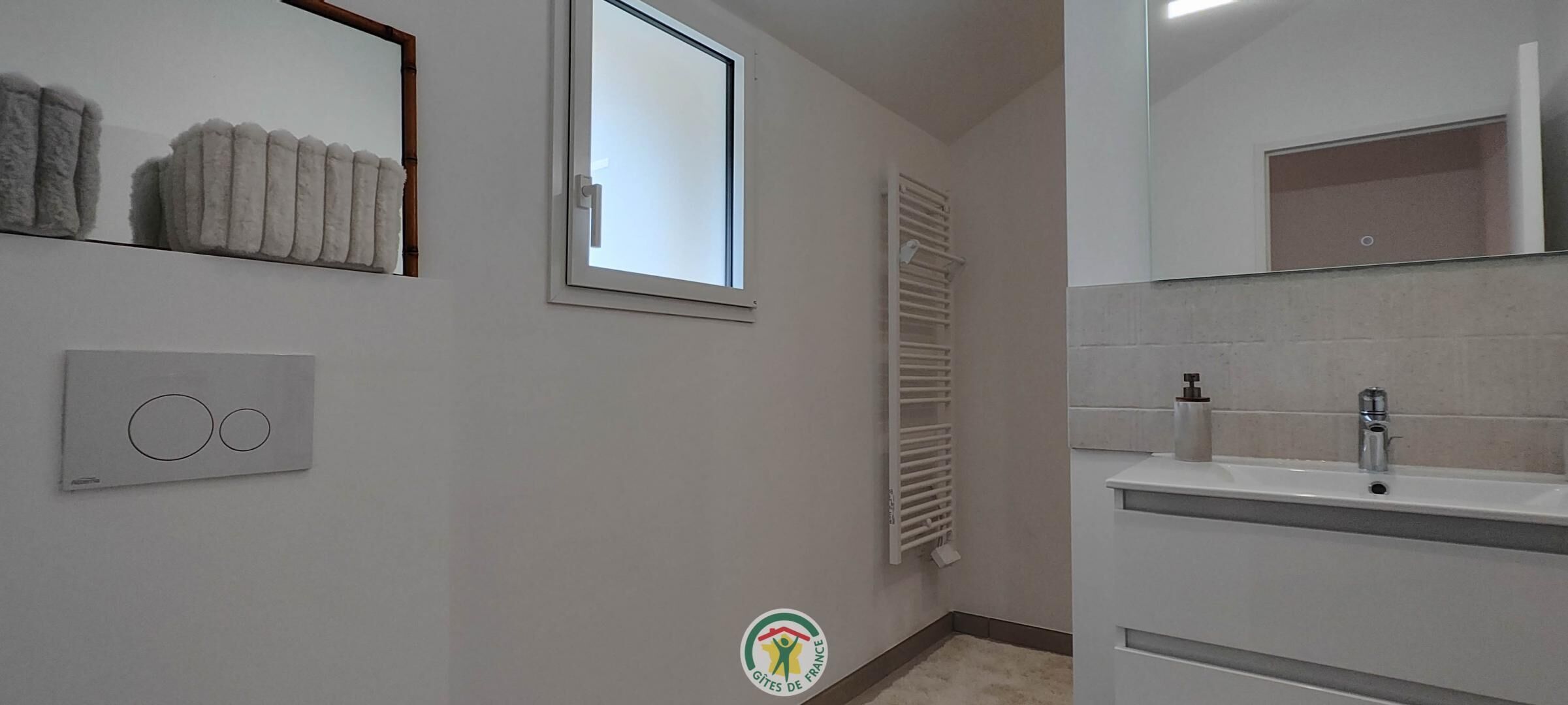 Un baño con ventana, un perchero, un radiador y un lavabo con espejo.