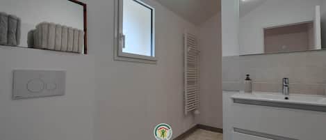 A bathroom with a window, a towel rack, a radiator, and a sink with a mirror.